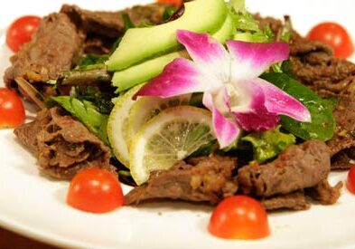 Beef salad garnished with flowers and tomatoes.