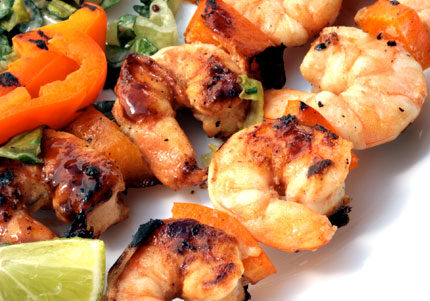 Grilled shrimp and vegetables with lime wedges.