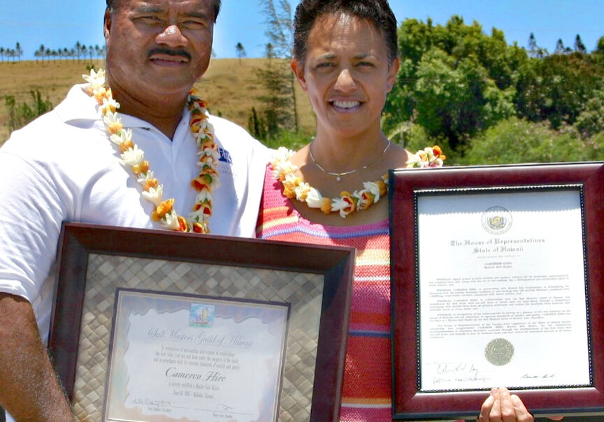 Two people holding framed certificates outdoors.