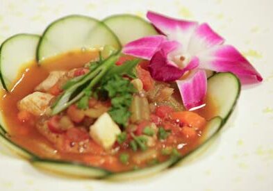 Colorful dish with cucumber and orchid garnish.