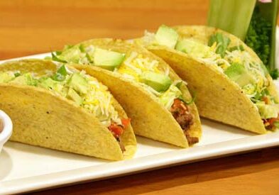 Three tacos with avocado and cheese.