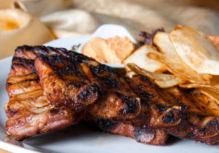 Grilled ribs with chips on plate.