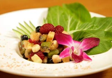 Fruit salad with orchid and green leaves.